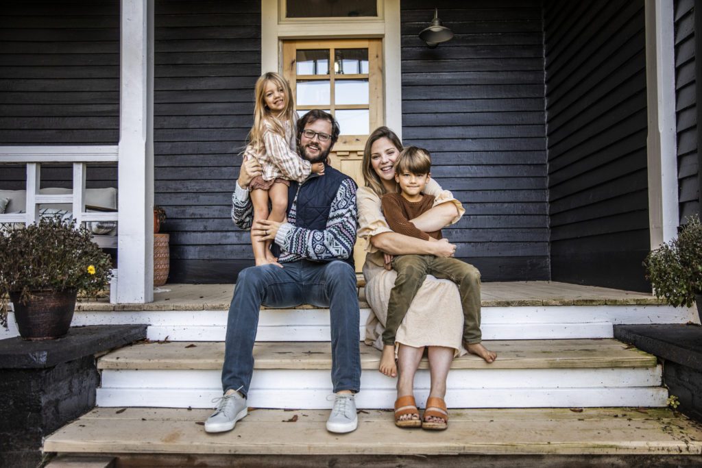 Portrait of young family in front of farmhouse