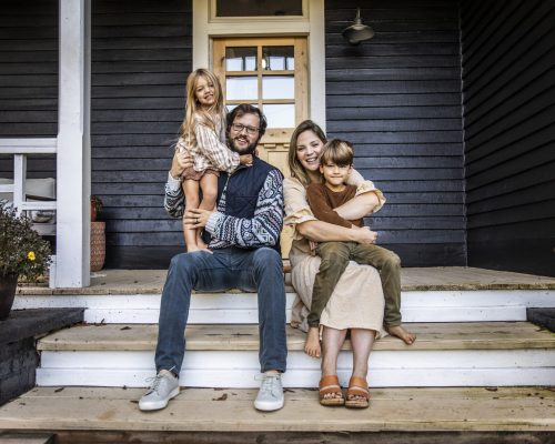 Portrait of young family in front of farmhouse